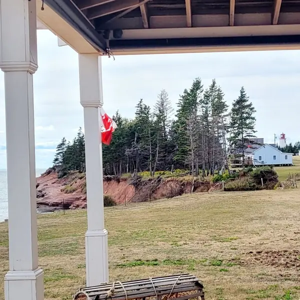 The porch, the flag and the lighthouse across the cove in September