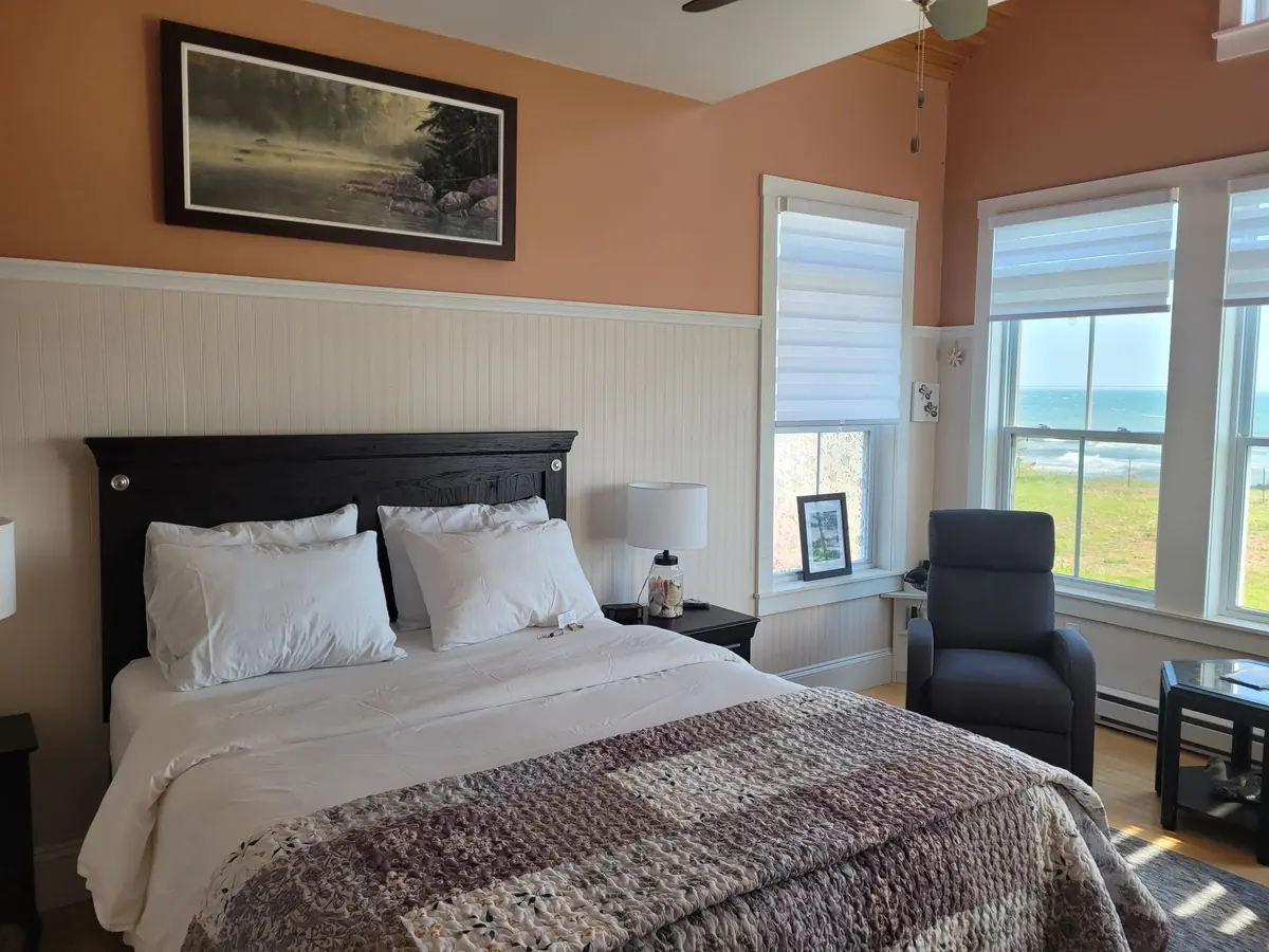 Guest bedroom with a dark headboard, framed art and a water view
