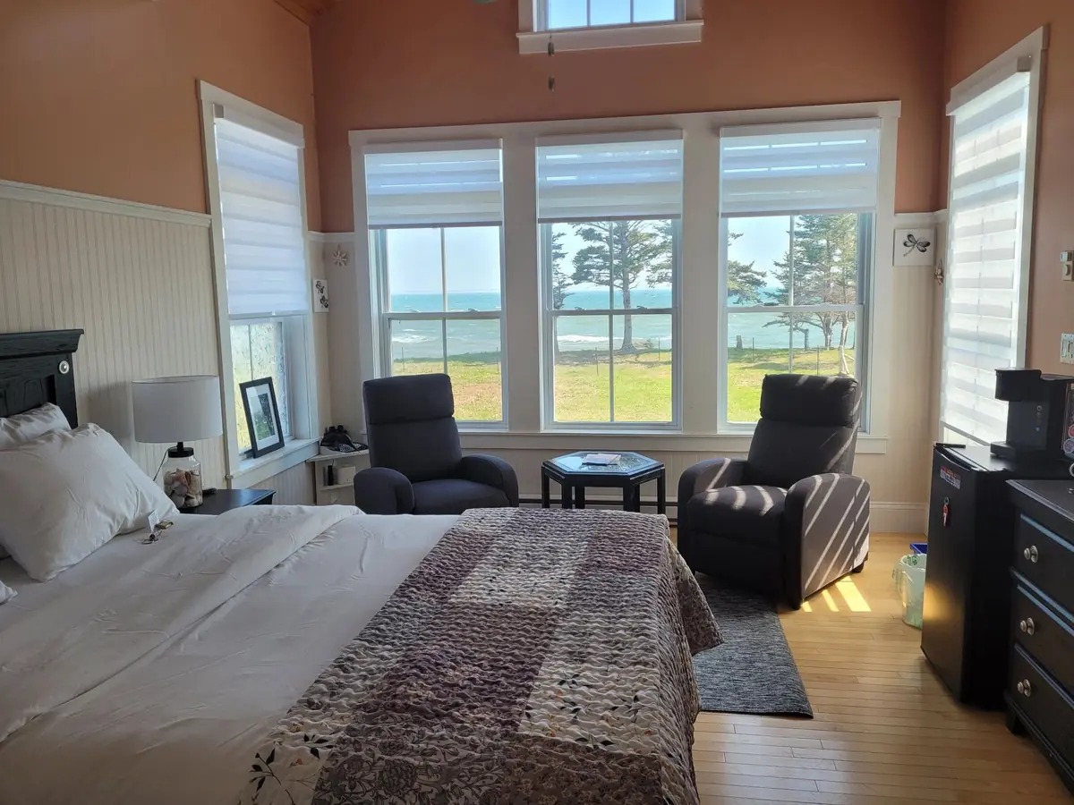 Guest bedroom with two recliners facing wide windows over the water