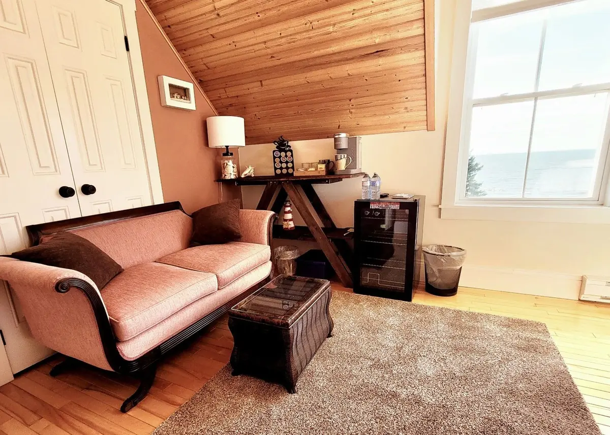 Sitting area with a pink chaise, dresser and television
