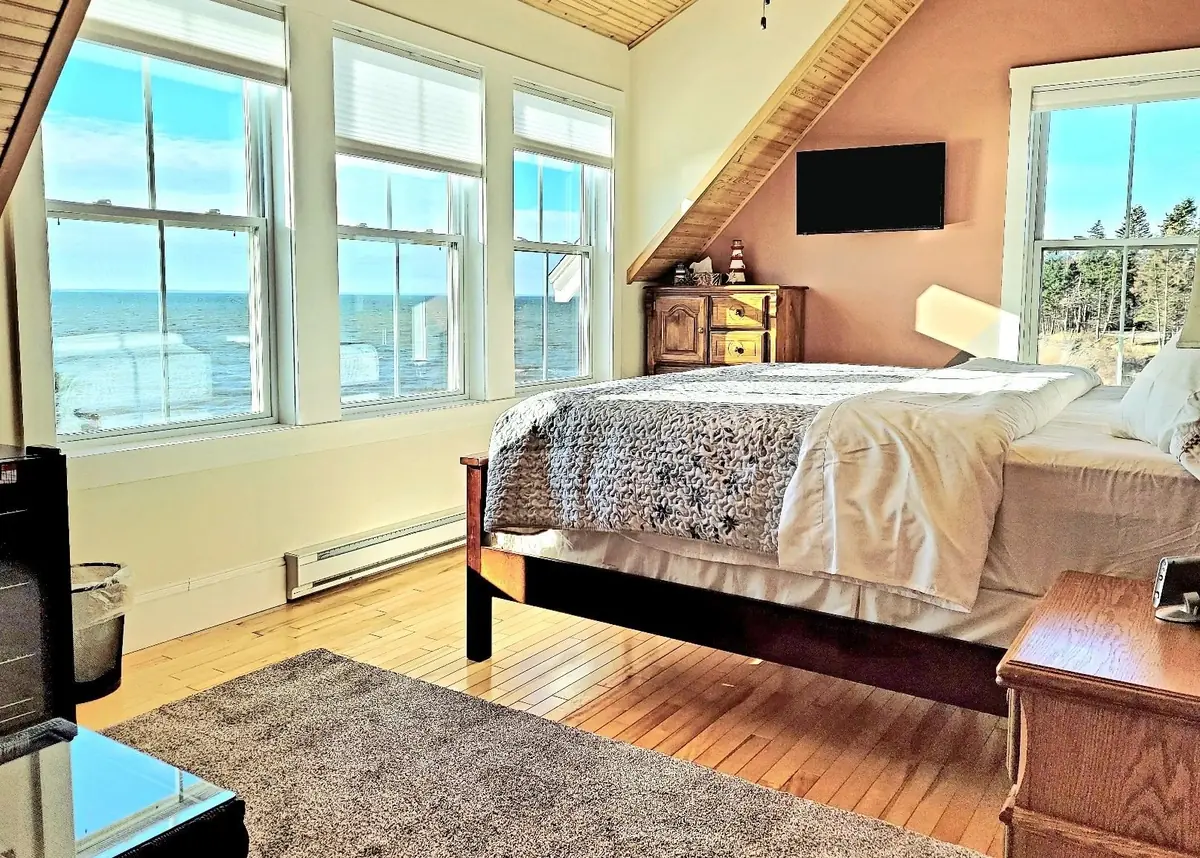 Guest bedroom with a water view through three windows