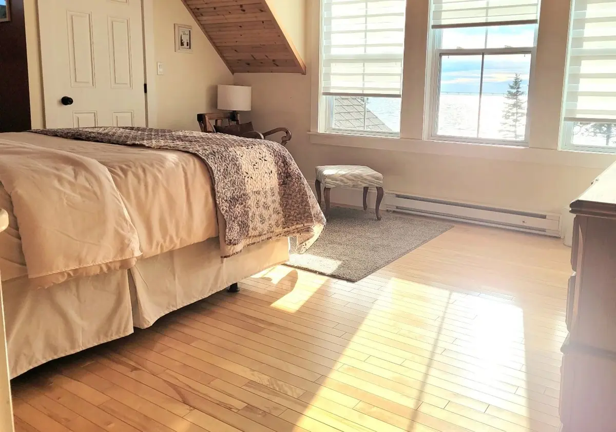 Corner of a guest bedroom with a small stool and a window to the water